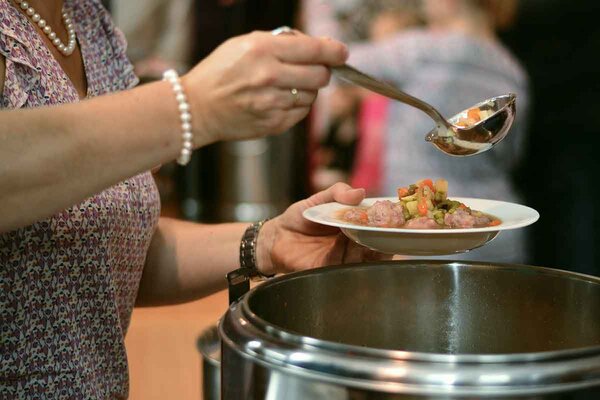 Bild von Mann der eine Suppe in einen Teller schöpft